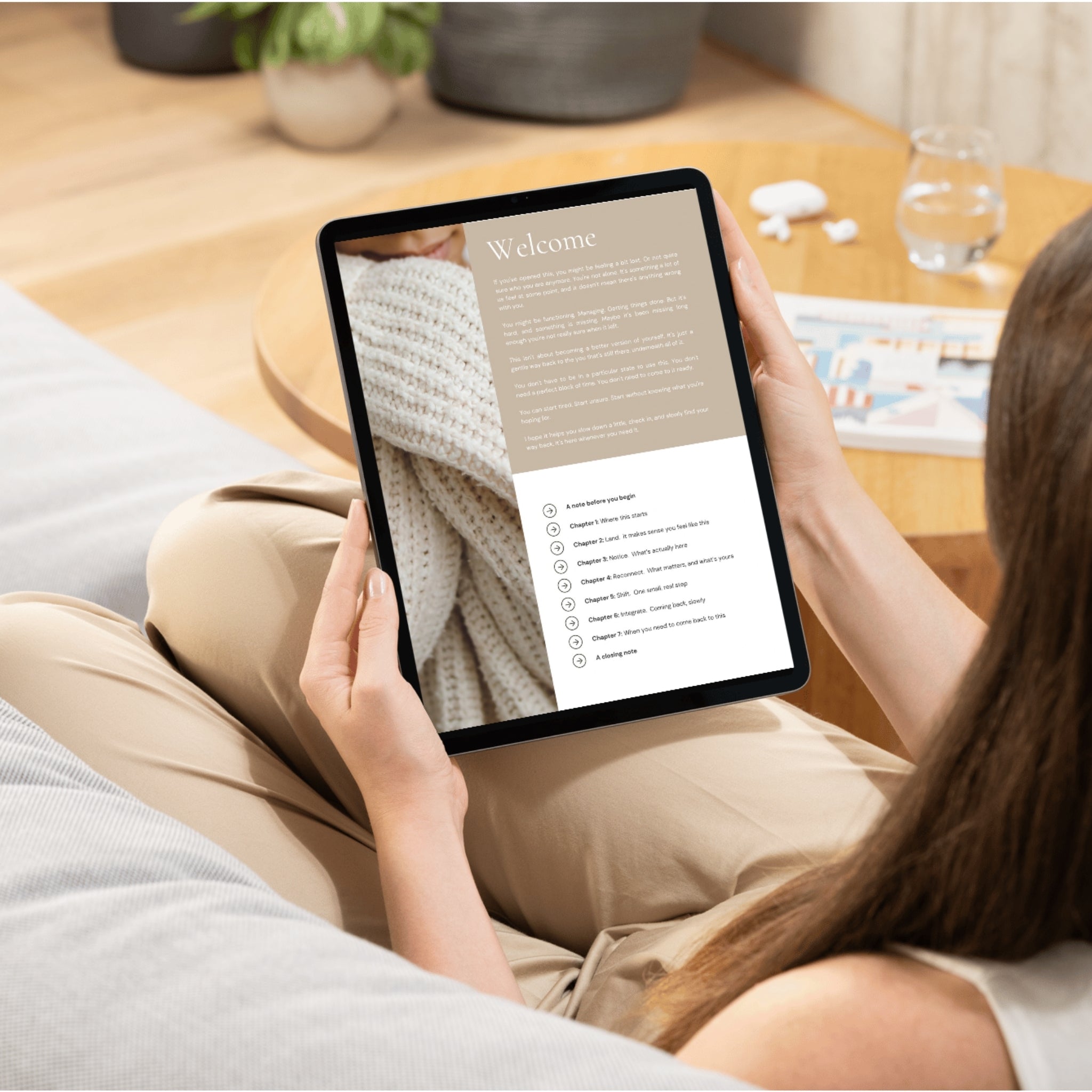 Person sitting on a couch comfortably holding a tablet or iPad with a welcome page and chapter summary displayed on the screen.